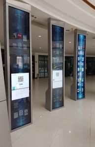 Three tall pillars with plasma screens onthem, displaying eBook covers. Two are showing QR codes