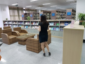 A section of the library with low shelving displaying recent issues of journals, magazines and newspapers. There are comfy seats and a woman in standing in the middle with her back to the camera.